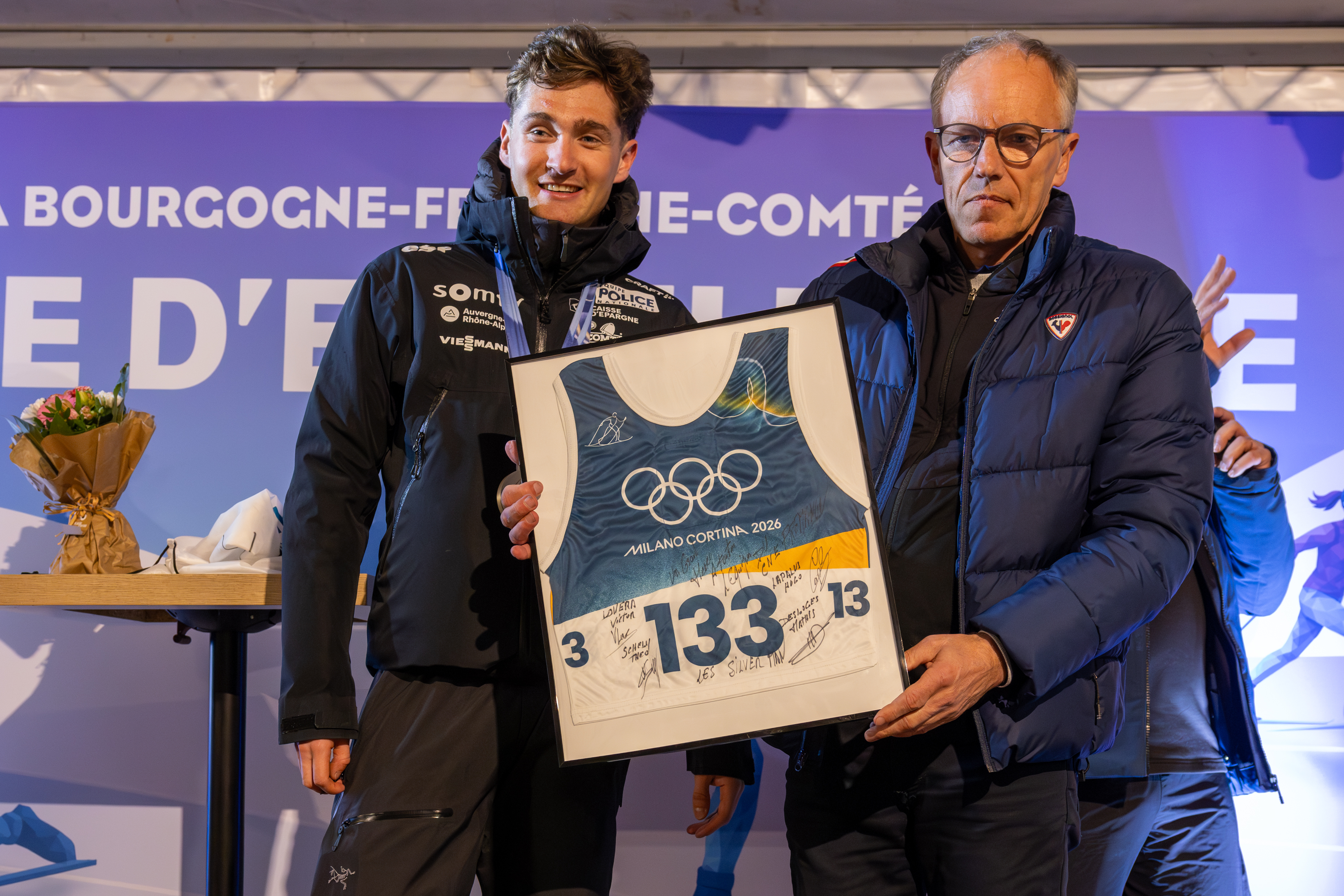 Mathis Desloges, triple médaillé olympique en ski de fond, remet son dossard à Nicolas Michaud, responsable du haut niveau au CNSNMM.  Photo : Xavier Ducordeaux