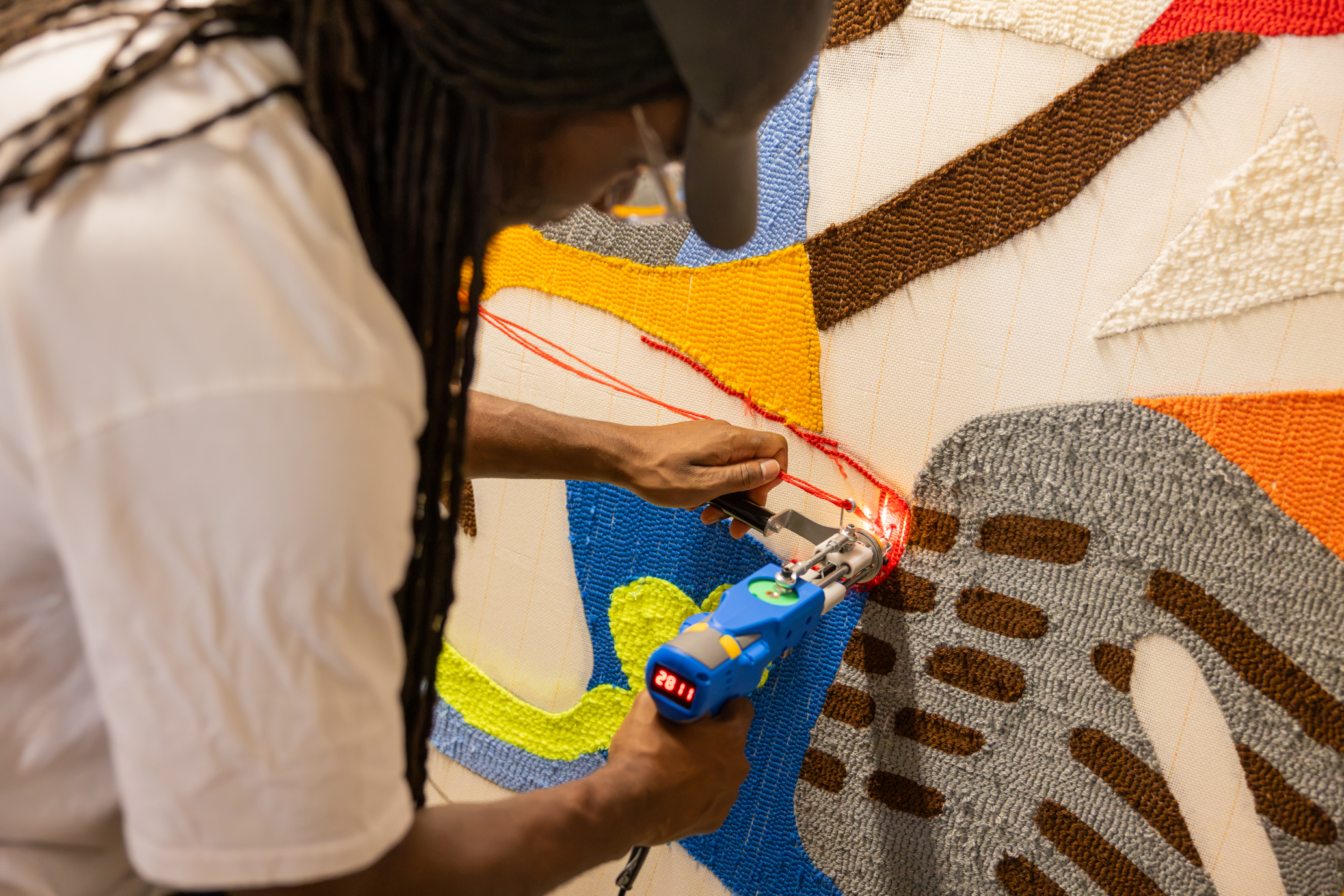 Pour tufter, l’artiste travaille « à l’envers » : il « tricote » au verso de la toile, avant de la retourner pour passer à l’étape de la tonte. Photo : Xavier Ducordeaux